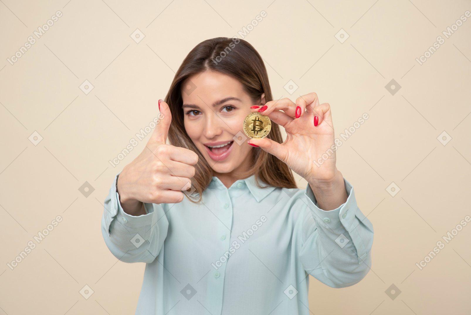 Chica joven atractiva que muestra un bitcoin y los pulgares para arriba