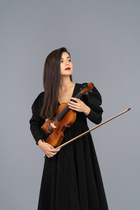 Close-up de uma jovem de vestido preto segurando o violino