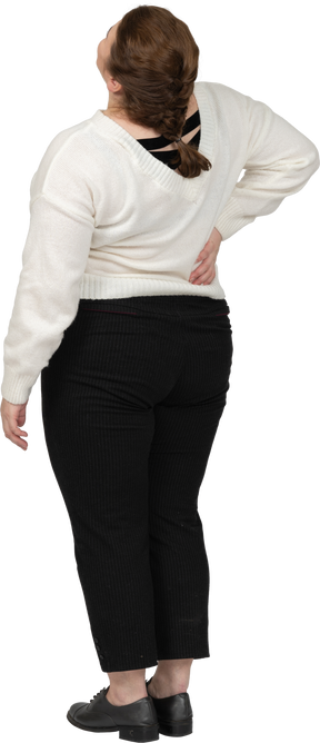 Plus size woman in white sweater suffering from pain in lower back