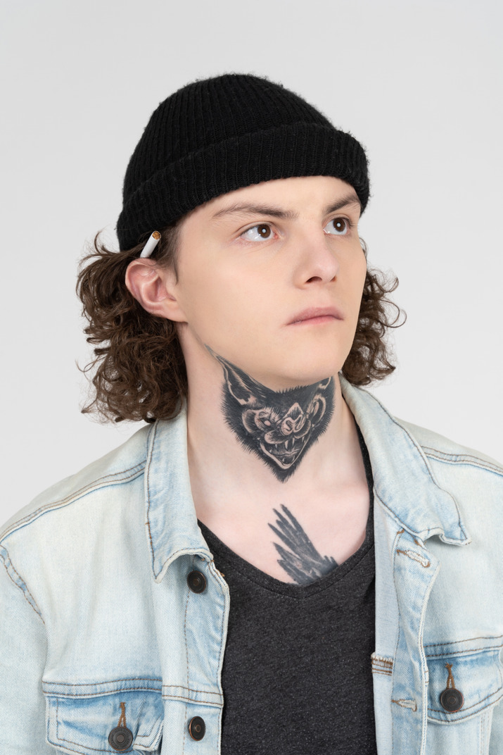 Portrait of a teenager with tattooed neck and cigarette on the ear