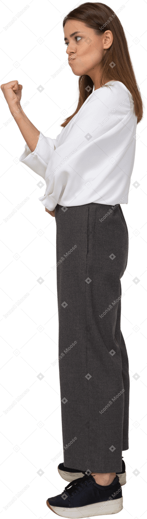 Side view of an angry young lady in office clothing clenching fist