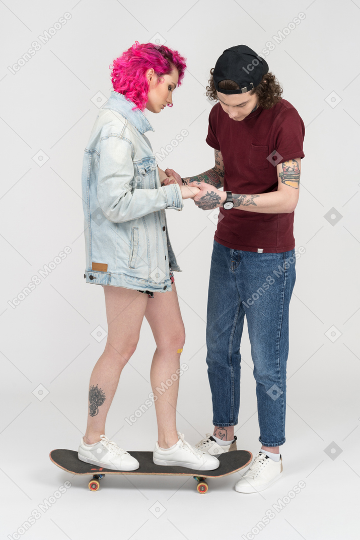 Jeune homme apprenant à sa petite amie à faire du skateboard