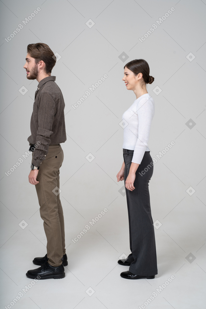Vue latérale d'un jeune couple souriant confus en vêtements de bureau