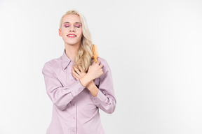 Young blond-haired person in a pastel violet shirt, doing their hair