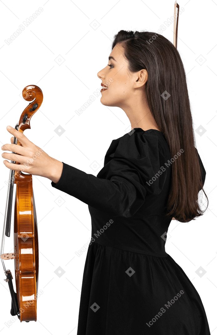 Vista lateral de una violinista en vestido negro extendiendo las manos