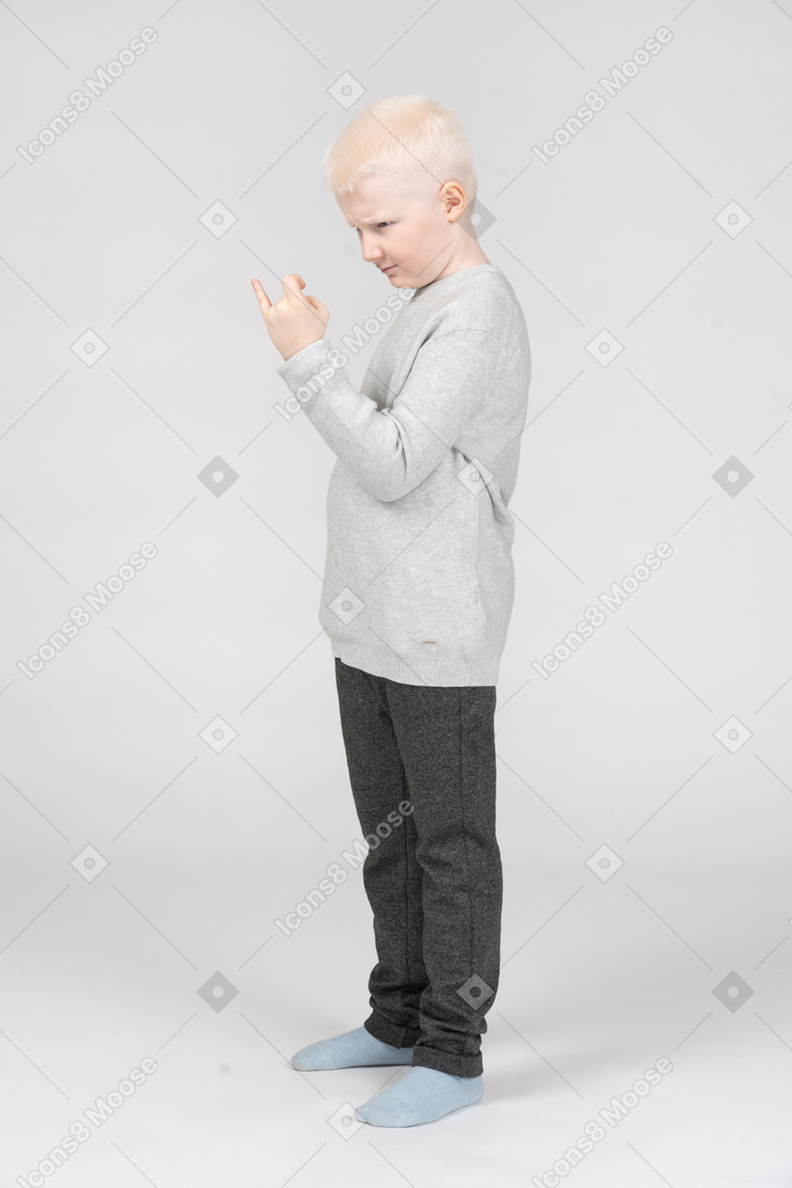 Side view of serious boy showing rock sign