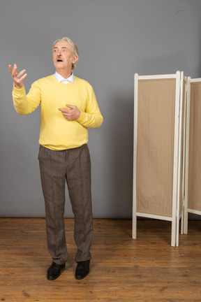 Front view of an inspired old man raising his hand