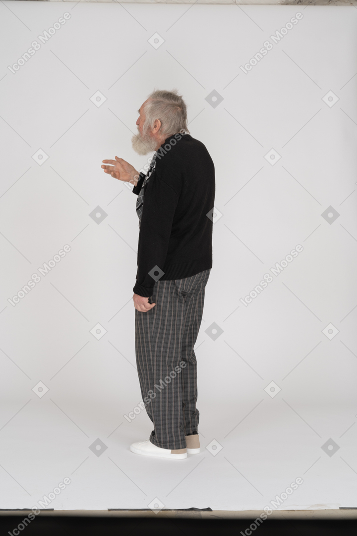 Vista trasera del anciano de pie con el brazo levantado