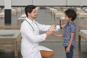 Male doctor handing toy to a boy