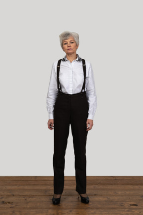 Vista frontal de uma senhora séria com roupas de escritório, parada na sala