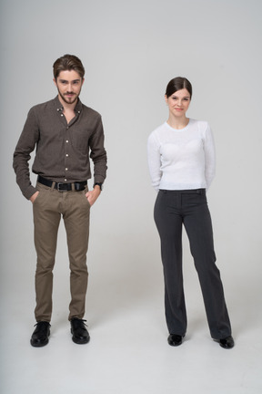Front view of a suspicious young couple in office clothing