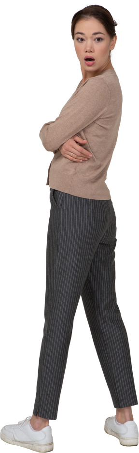 Vista posteriore di tre quarti di una giovane donna sbalordita in maglione beige che attraversa le mani