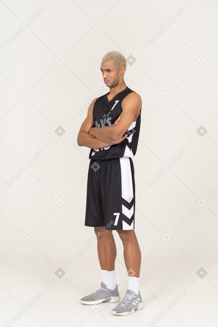 Three-quarter view of a withdrawn young male basketball player crossing arms