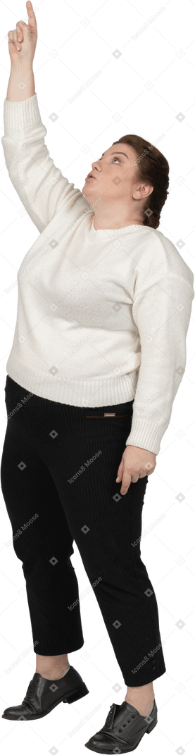 Vista lateral de uma mulher gorda em roupas casuais apontando para cima