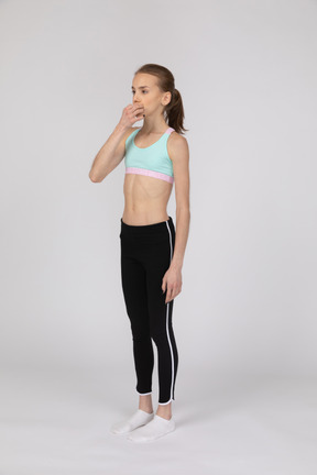 Una adolescente en ropa deportiva tocándose la boca.