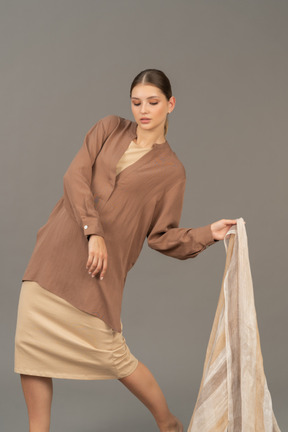 Mujer joven en ropa beige posando con bufanda