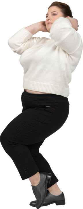 Plus size woman in white sweater standing with hands behind head