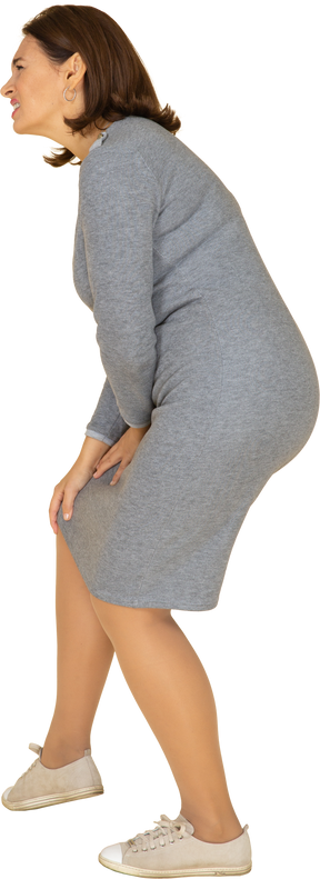 Vue latérale d'une femme en robe grise touchant le genou