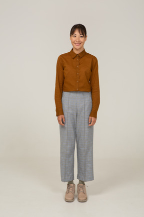 Front view of a smiling young asian female in breeches and blouse standing still