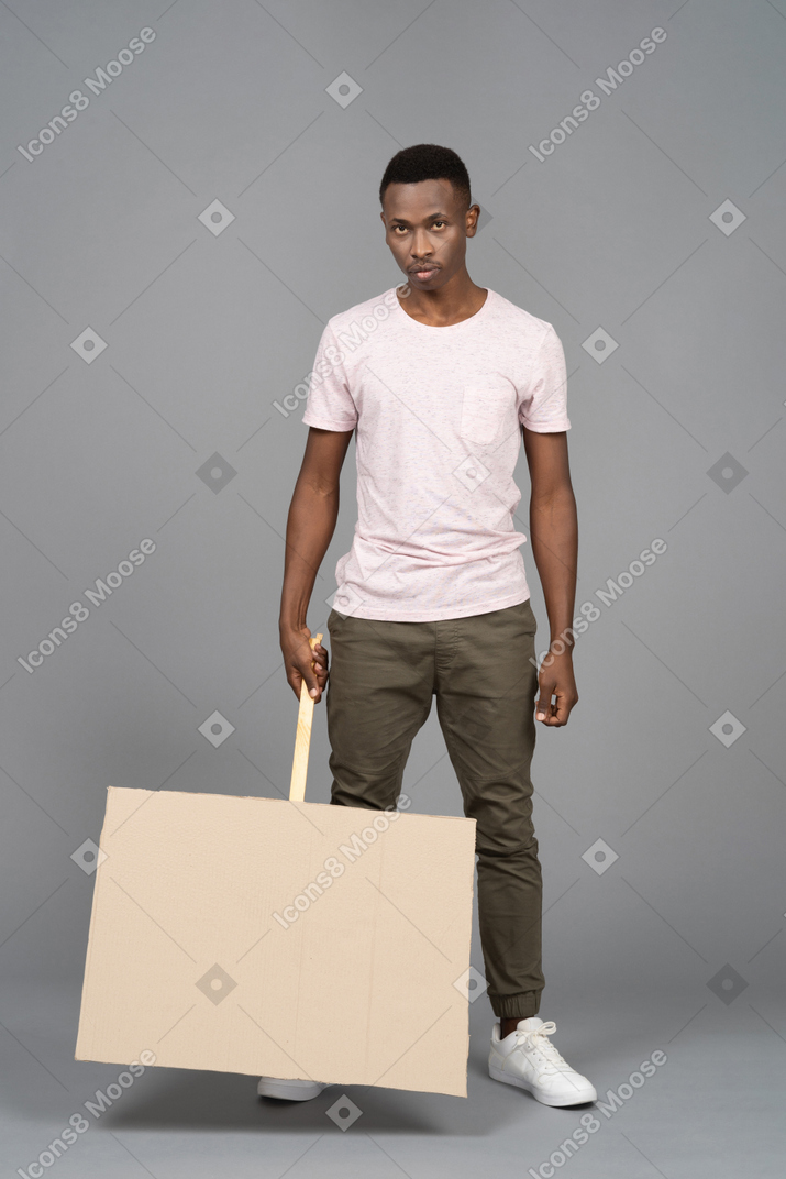 A serious young man holding a blank poster upside down
