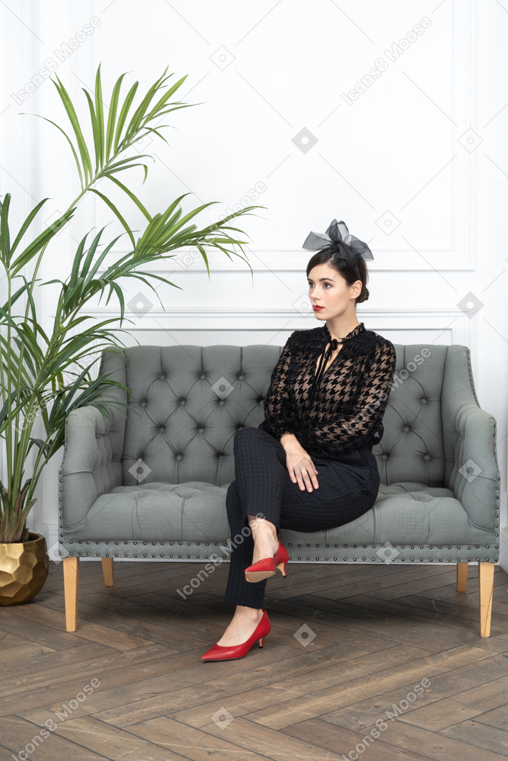 Woman in blouse sitting cross legged on couch