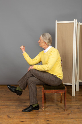 Hombre sentado en una silla y agitando el puño