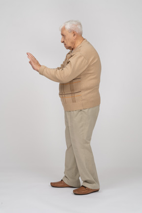 Вид сбоку на старика в повседневной одежде, показывающего стоп-жест