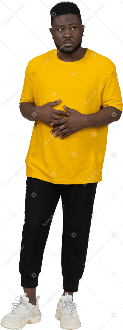 Front view of a young dark-skinned man in yellow t-shirt holding hands on stomach