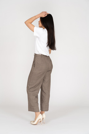Side view of a young lady in breeches and t-shirt touching her head