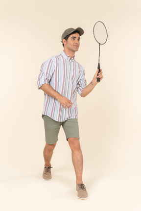 Laughing young caucasian guy holding racket