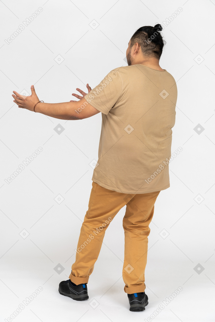 Asian man raising both hands on chest level back to camera