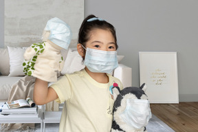 A little girl in face mask with toys in face masks