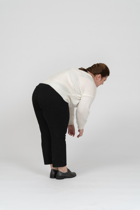 Vista lateral de uma mulher plus size com roupas casuais se abaixando