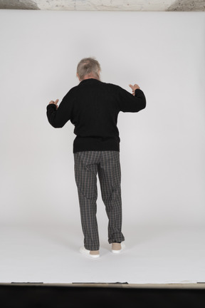 Back view of elderly man standing with bent arms