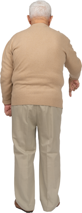 Rear view of an old man in casual clothes pointing down with finger