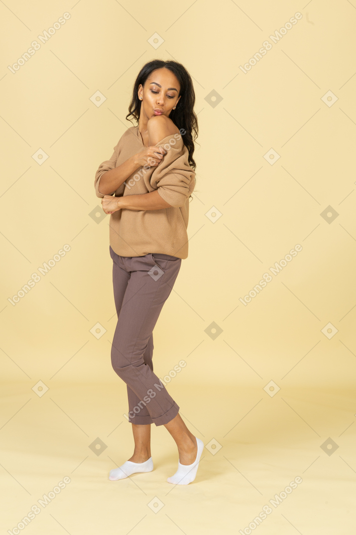 Vista lateral de una mujer joven de piel oscura tocando su hombro