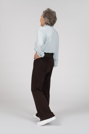 Vista posteriore di tre quarti di una donna anziana con una mano sull'anca