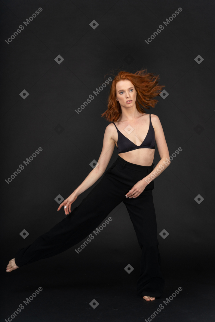 A frontal view the young beautiful girl posing on the black background and dancing