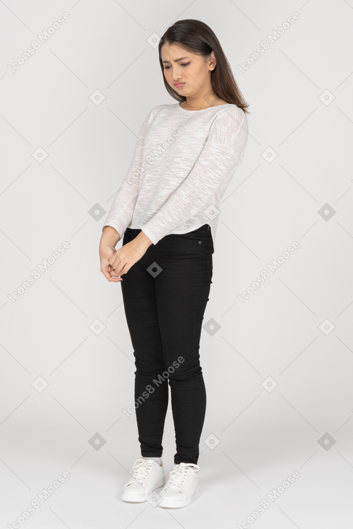 Frown young woman holding hands together and looking down