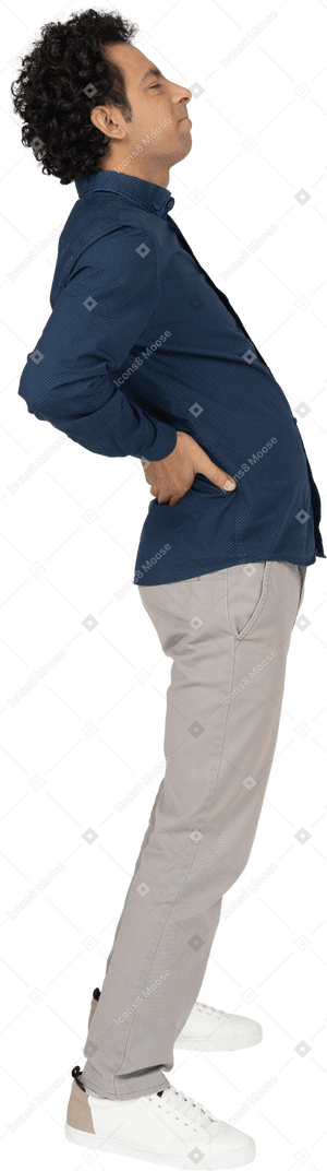 Side view of a man in casual clothes suffering from pain in lower back