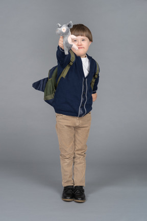 Retrato de un niño pequeño con una mochila sosteniendo un peluche de lechón