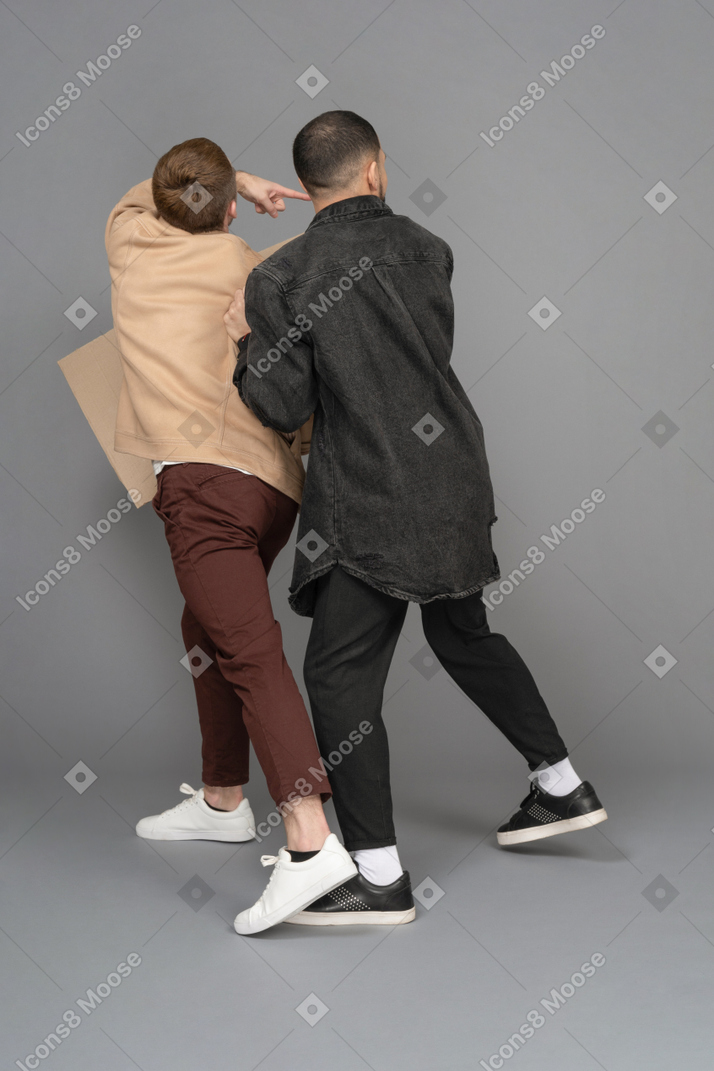 Vista traseira de dois jovens com um outdoor olhando por cima dos ombros em pânico