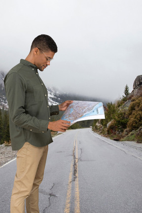 A man standing on the side of a road looking at a map