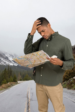 A man standing on the side of a road looking at a map