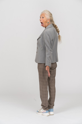 Vista traseira de uma senhora idosa de terno mostrando a língua