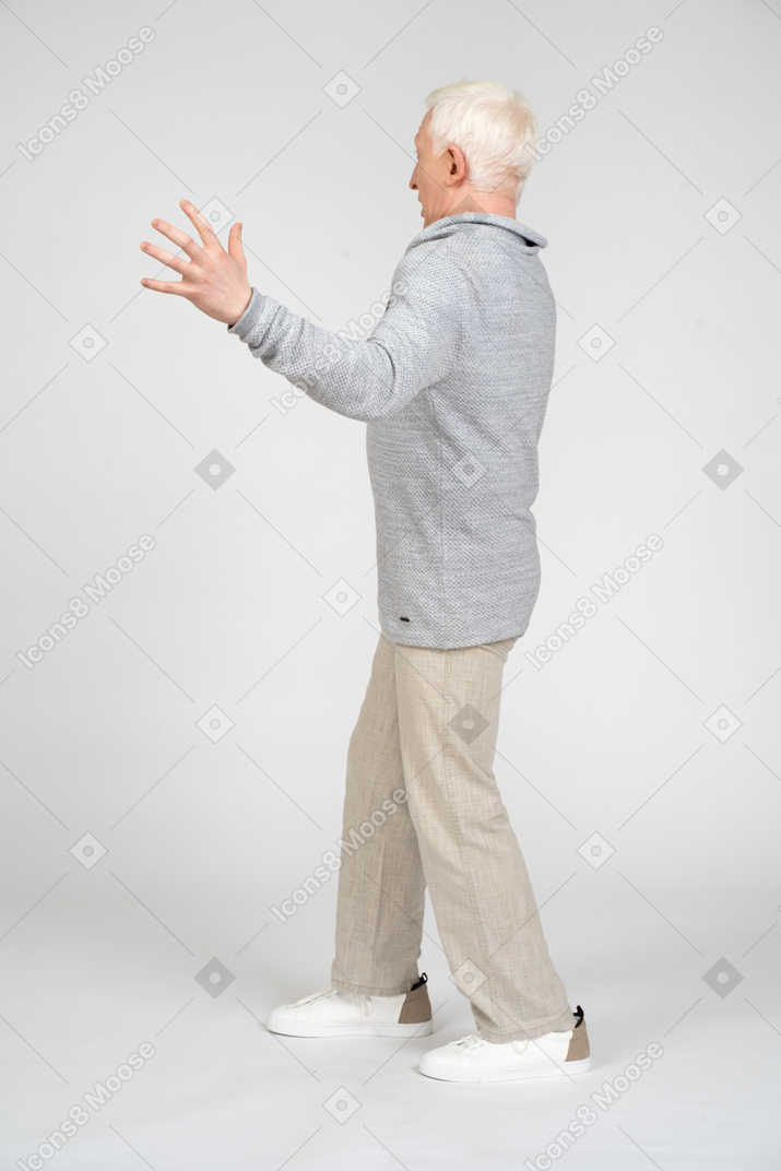 Vista laterale di un uomo in piedi con il braccio piegato e le dita allargate