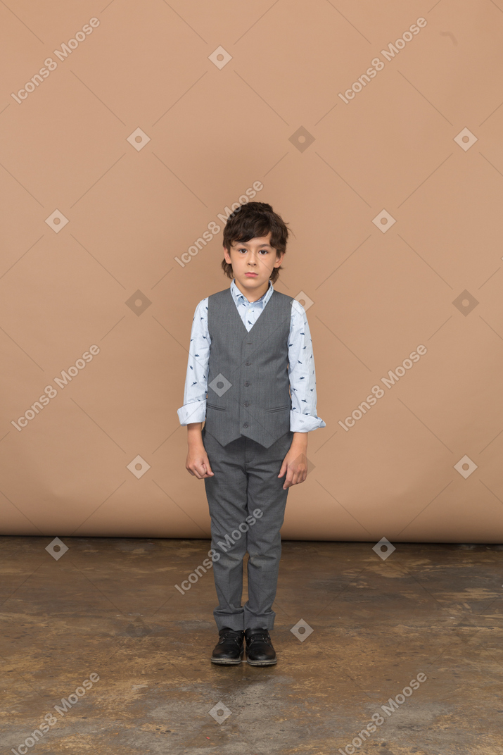 Front view of a shy boy in grey suit standing still