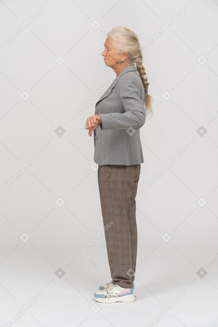 Vista laterale di una vecchia signora in abito che mostra il pollice verso il basso