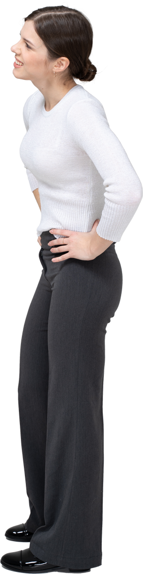Vue latérale d'une jeune femme en vêtements décontractés debout avec les mains sur les hanches