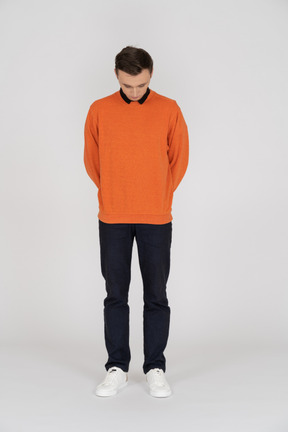 Junger mann im orangefarbenen sweatshirt stehend